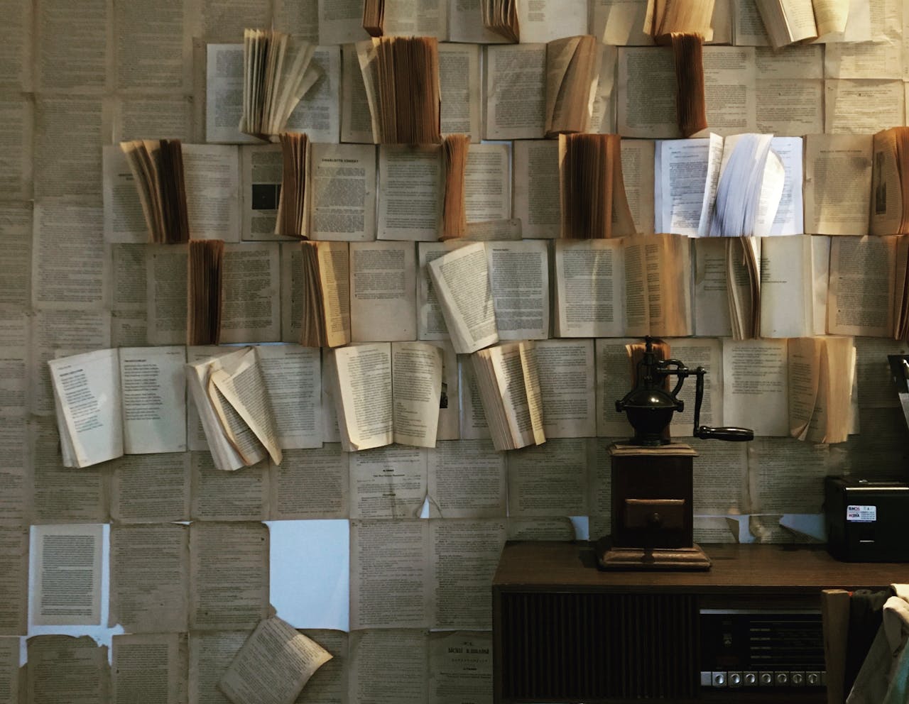 A wall adorned with open vintage books and an antique coffee grinder enhances a cozy ambiance.