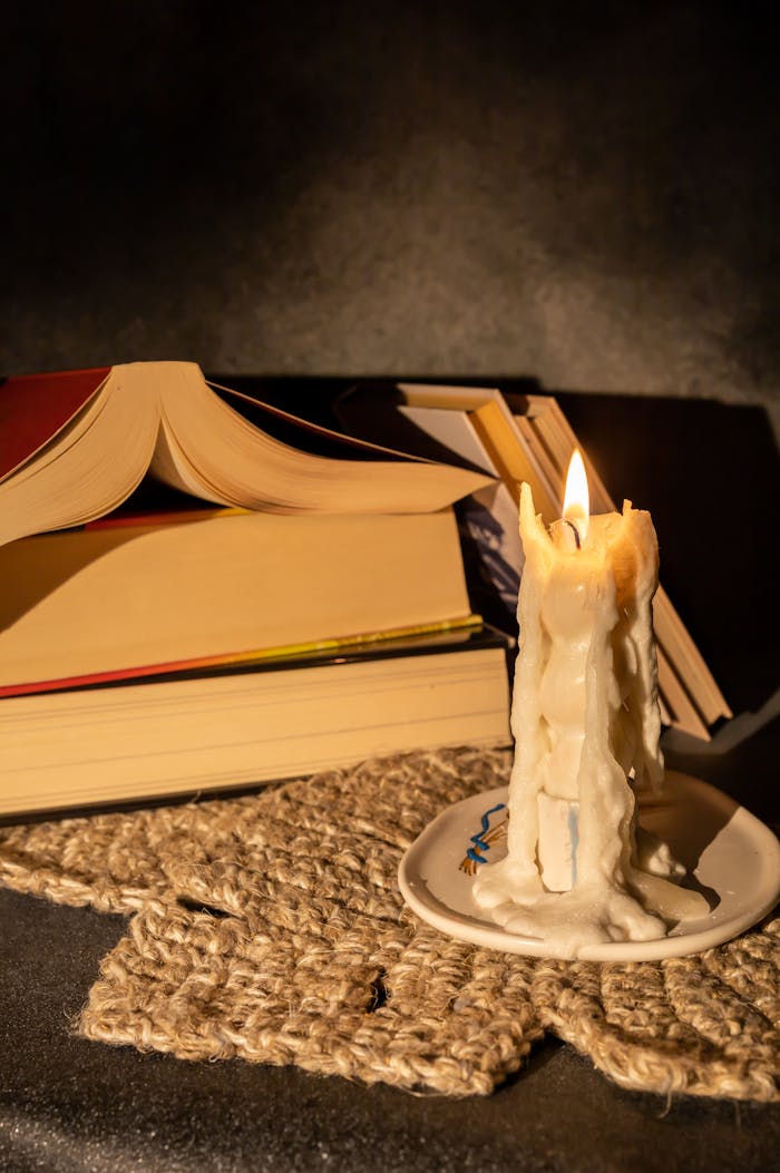 Warm, intimate scene with a candle and open books on woven mat. Ideal for reading themes.